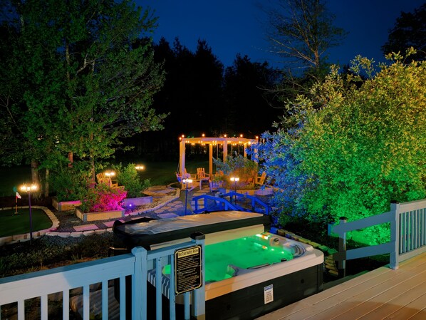 Ein Whirlpool mit Sicherheitsregeln, ein Pavillon mit Lichterketten und eine Holzterrasse.