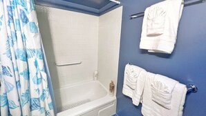 Kylpyhuoneessa on kylpyamme, suihku ja wc. Pyyhkeet on ripustettu pyyhetelineeseen, ja ikkunassa on lehvikuvioinen verho.
