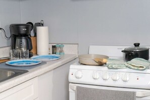 Eine Küche mit einem Herd, einer Kaffeemaschine und verschiedenen Küchenutensilien auf der Arbeitsfläche.