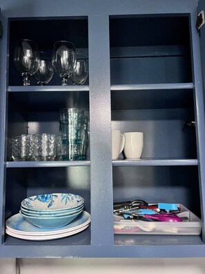 A cabinet with shelves containing glassware, plates, and utensils. - Simple Studio 1 block from Beach (Honolulu)