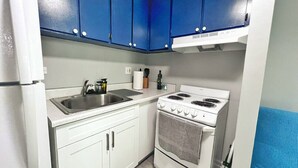 A compact kitchen with white cabinets, a double sink, and a white stove.
