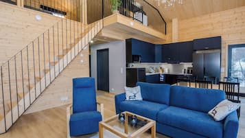 Een modern interieur met een trap, een zithoek met een bank en fauteuils, een keuken en een eethoek.