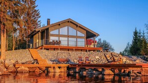 A modern house with a large deck and a stone wall. - Lakeside villa by Interhome (Nurmes)