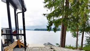 A pathway leading to a wooden deck with a view of a lake and trees. - Lakeside villa by Interhome (Nurmes)
