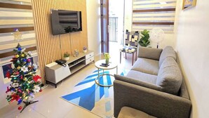 Una sala de estar moderna con televisor, sofá y un árbol de Navidad.
