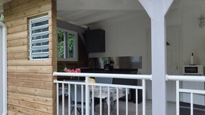Eine Holzhütte mit Küchenbereich, inklusive Esstisch und Stühlen, sowie einem weißen Geländer.