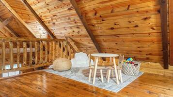 Ein Holzinterieur mit Holztisch und -stühlen, einem gewebten Pouf und einem Korb.