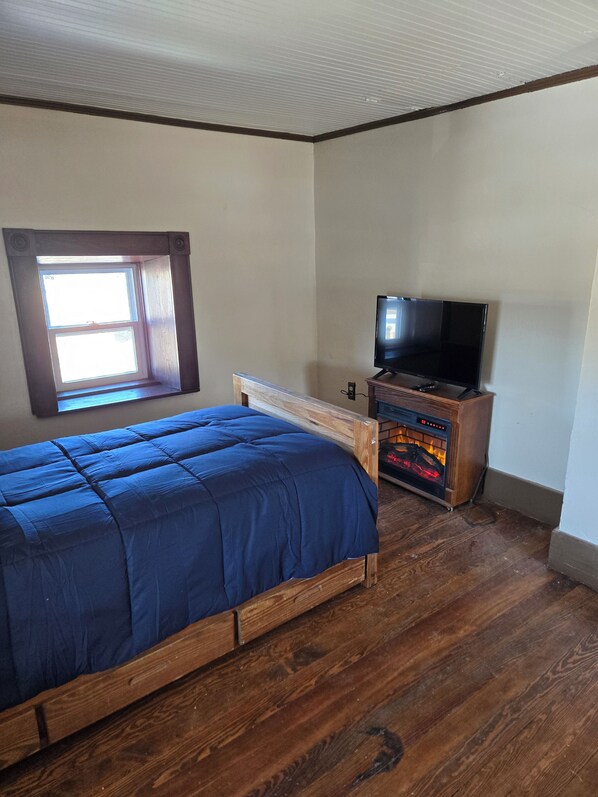 Une chambre à coucher avec un lit, une télévision et une cheminée.