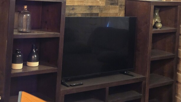 Sala de estar con paneles de madera, un televisor de pantalla plana y estanterías empotradas.