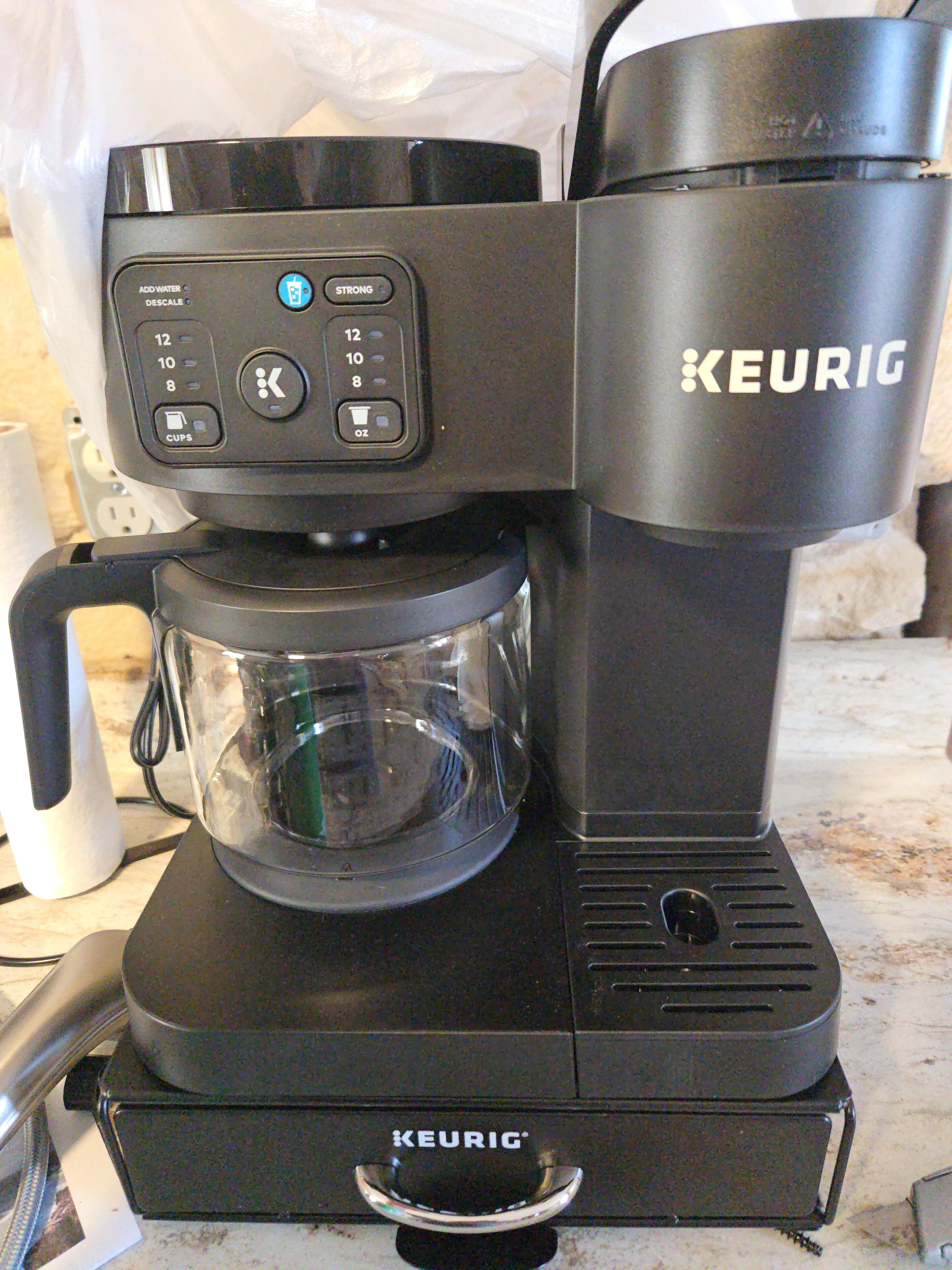 A Keurig coffee maker with a clear carafe and a water reservoir.