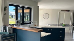 A modern kitchen with a central island, a built-in oven, and a large window offering a view of the outdoors.