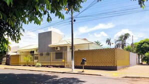 A modern house with a fenced yard, a paved driveway, and a street view. - Martins Cozy House in Foz do Iguaçu  (Parque Residencial Italia Foz do Iguaçu)