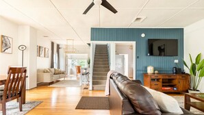 Un salon spacieux avec un canapé en cuir, une table à manger en bois et un escalier menant à l’étage supérieur.