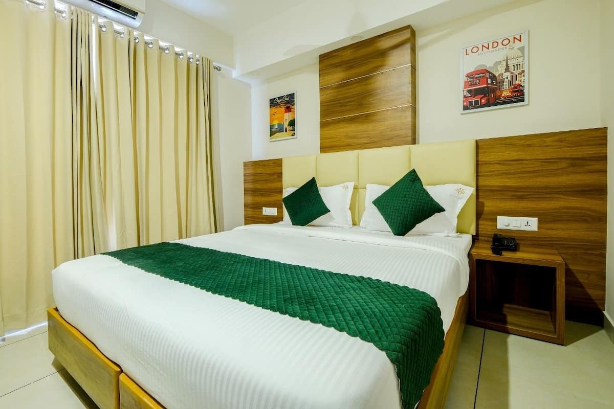 A neatly made bed with a green blanket, wooden headboard, and a London-themed poster on the wall.