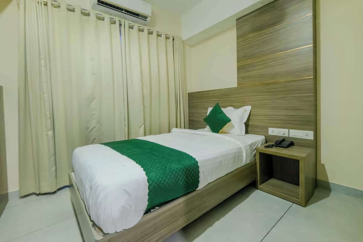 A hotel room with a bed, a nightstand, and a wall-mounted telephone.