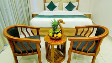 Una habitación de hotel con una cama, dos sillas de madera y una pequeña mesa con un frutero.
