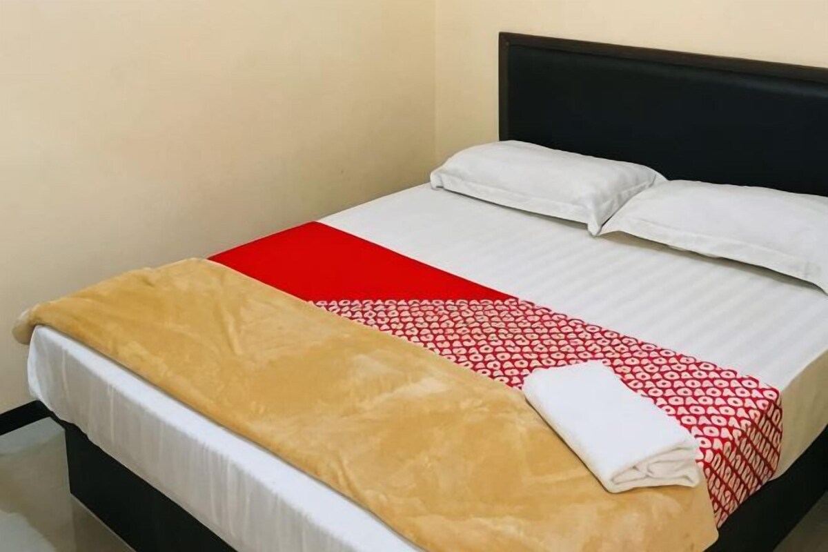 A bed with a white and red bedspread, a brown blanket, and a white pillow.