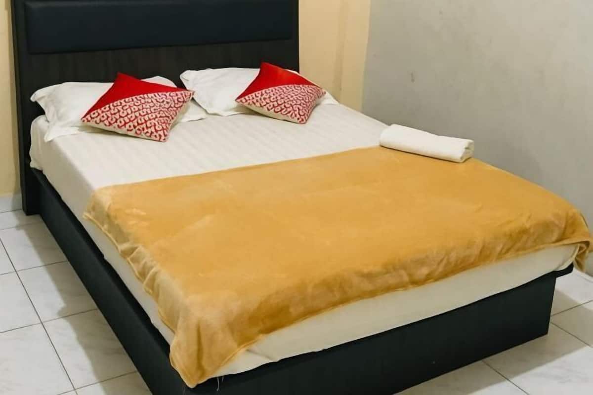 A bed with a white mattress, a brown blanket, and two red and white patterned pillows.