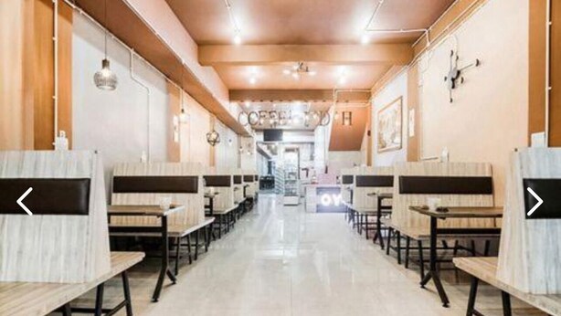 A long, narrow restaurant with booths and tables, a tiled floor, and a central walkway. - CJ HOMESTAY (Batam)