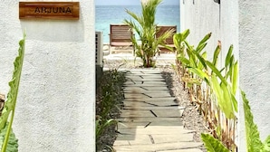 A pathway leading to beachside seating with a sign reading "ARJUNA".