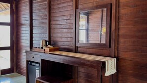 A wooden-paneled room with a small table, a refrigerator, and a bench.