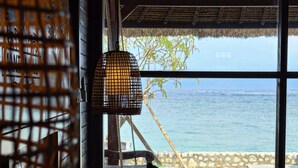 A room with a large window overlooking the sea, a hanging light fixture, and a woven basket.
