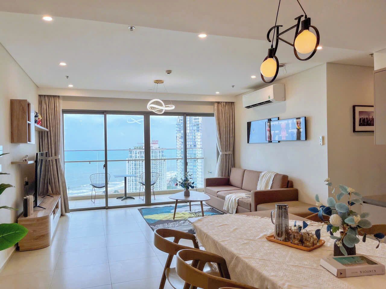 Una sala de estar moderna con un amplio ventanal corredera que da a un balcón con vistas a la ciudad.