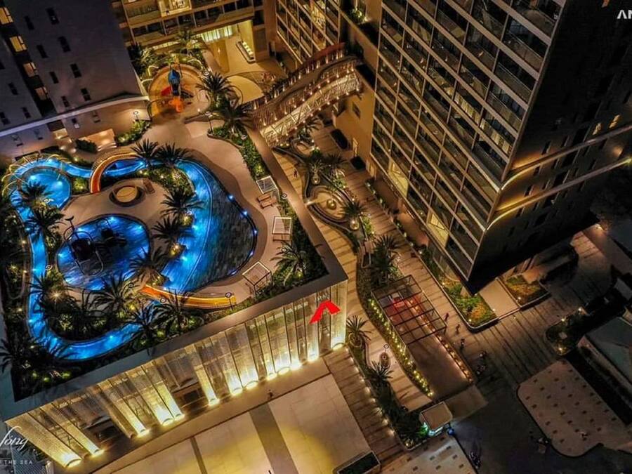 Un hotel con una amplia piscina cubierta rodeada de palmeras y una fuente central.