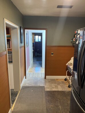 A hallway with a refrigerator, a door leading to a bathroom, and a mat at the entrance. - Delightful 3-bedroom COZY ROOMY  house  in Beautiful Powell WYOMING with WiFi ! (Powell)