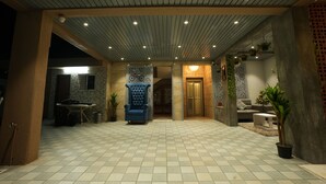A spacious indoor area with a tiled floor, a blue armchair, and a door leading to another room. - Hotel Mountain View (Nashik)