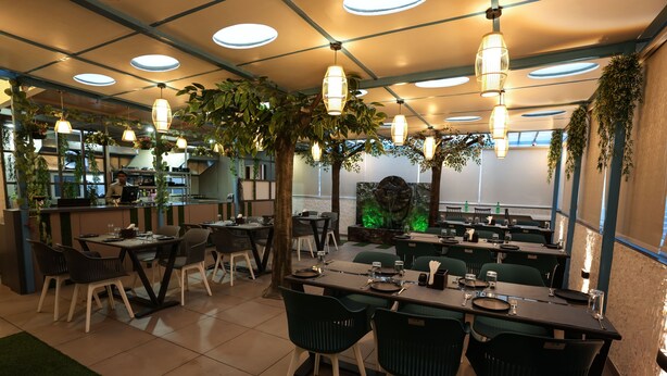 A restaurant with indoor seating, hanging plants, and pendant lighting. - Hotel Mountain View (Nashik)