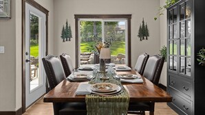 A dining room with a wooden table set for four, surrounded by dark leather chairs. A black cabinet with glass doors is to the right. - Four Bedroom Retreat Near Hayden Lake: Game Room, Family Fun (Coeur d'Alene)