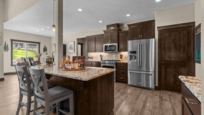 A modern kitchen with dark wood cabinets, stainless steel appliances, and a granite countertop. - Four Bedroom Retreat Near Hayden Lake: Game Room, Family Fun (Coeur d'Alene)