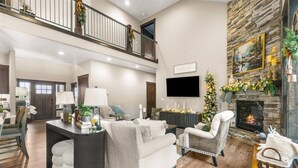 A spacious living room with a fireplace, a high ceiling, and a stone accent wall. - Four Bedroom Retreat Near Hayden Lake: Game Room, Family Fun (Coeur d'Alene)
