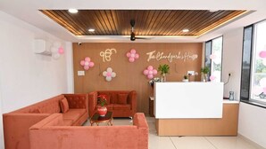 A reception area with a wooden reception desk, two sofas, and a potted plant. - The Byke Business - Chandigarh House (Bhopal)