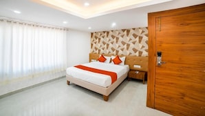 A bedroom with a bed, nightstand, wooden door, and a ceiling fan. - The Byke Business - Chandigarh House (Bhopal)