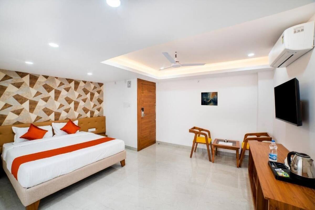 Een hotelkamer met een bed, een bureau, stoelen, een televisie en een airconditioningsysteem.