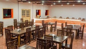 A restaurant with multiple wooden tables and chairs, a stone counter, and a brick wall. - DESERT LEELA RESORT (Jaisalmer)