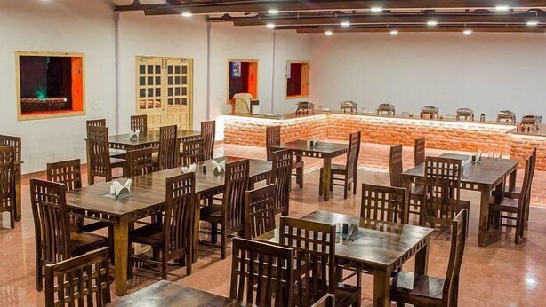 Un ristorante con diversi tavoli e sedie di legno, un bancone in pietra e un muro in mattoni.