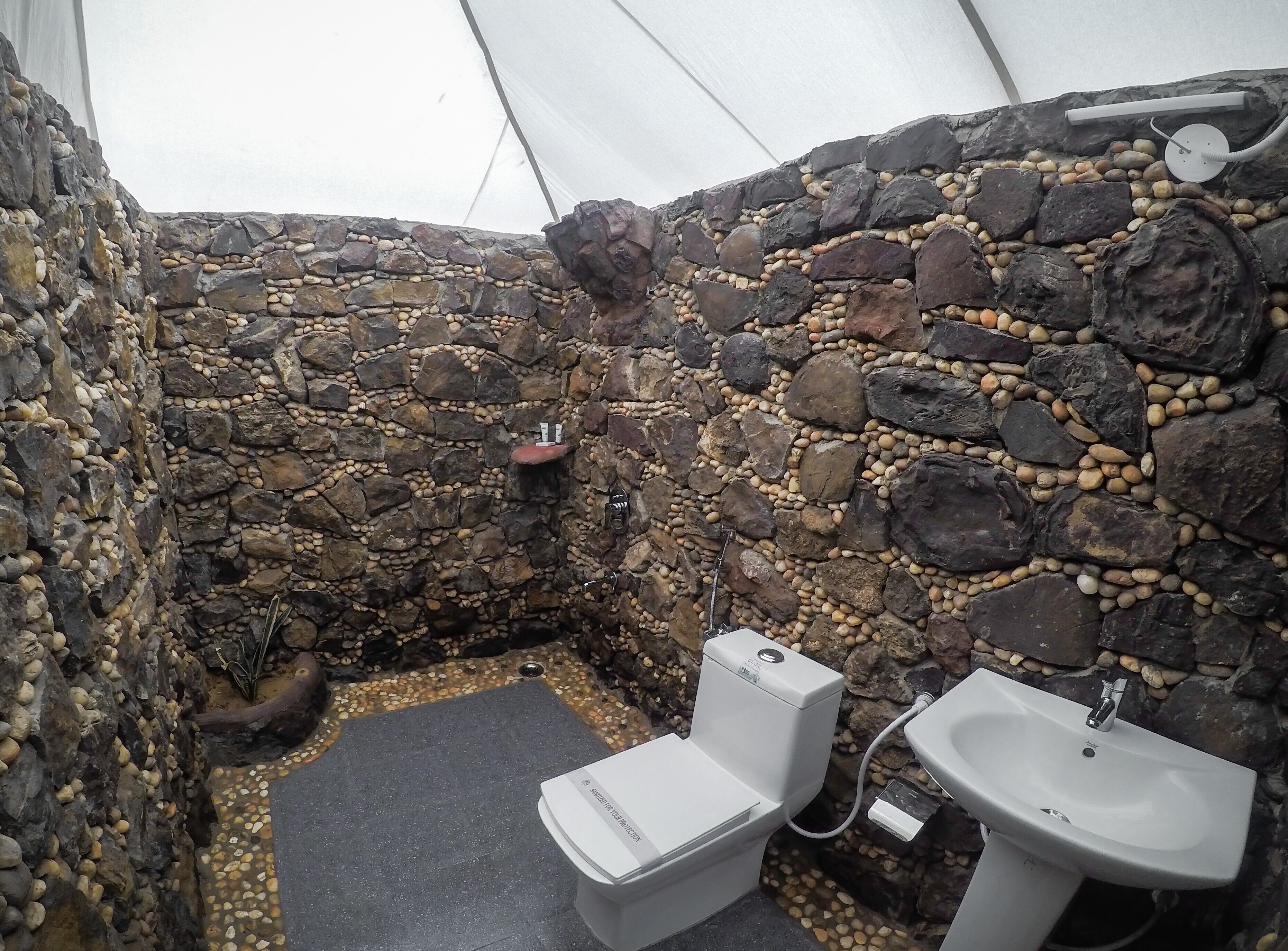 A stone-walled bathroom with a toilet and sink.