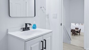 Ein modernes Badezimmer mit einem weißen Waschtisch, einem schwarzen Wasserhahn und einem Spiegel mit Beleuchtung.