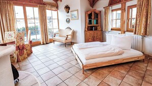 Ein Schlafzimmer mit einem Holzbett, einem Sessel, einem Schrank und Blick durch große Fenster.