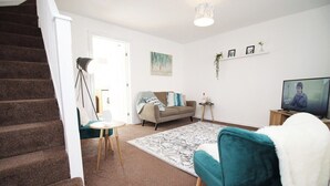 A living room with a sofa, a coffee table, a rug, and a television. - Gwent View by Tŷ SA (Newport)