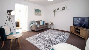 A living room with a sofa, a coffee table, a TV, a lamp, and a patterned rug. - Gwent View by Tŷ SA (Newport)