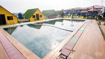 A swimming pool with a wooden deck and colorful buildings in the background.