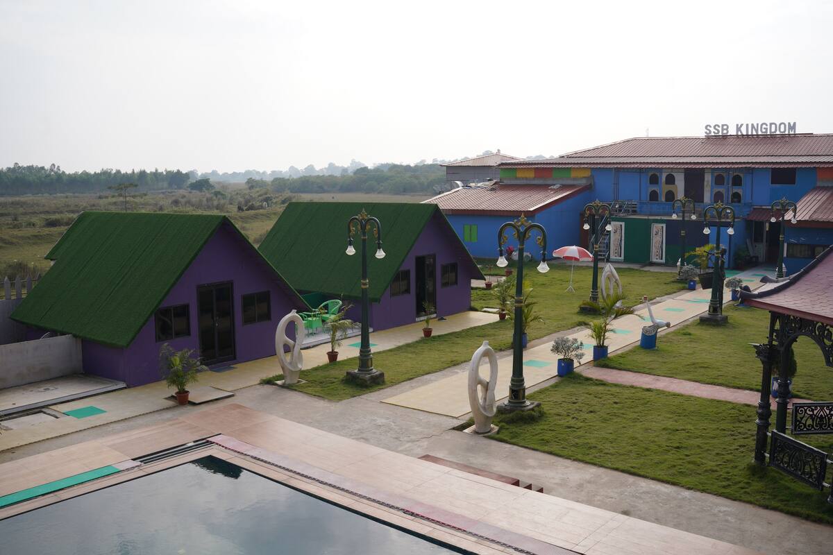 A resort with multiple colorful buildings, a swimming pool, and a well-maintained lawn.