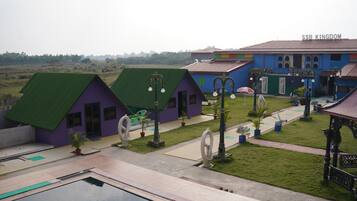 A resort with multiple colorful buildings, a swimming pool, and a well-maintained lawn.