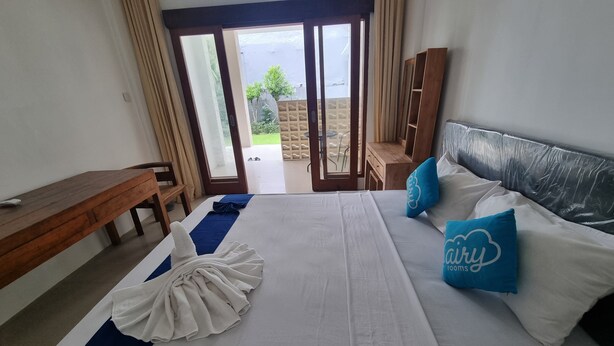 A hotel room with a bed, a desk, and a view of the outdoors. - Mulia Cottage Jimbaran (Jimbaran)
