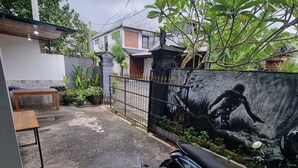 A motorcycle parked in a driveway with a concrete wall and a mural in the background. - Mulia Cottage Jimbaran (Jimbaran)