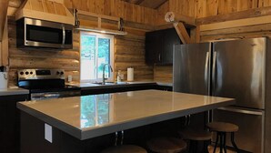 Una cocina moderna con paredes de madera, electrodomésticos de acero inoxidable y una isla central con taburetes.